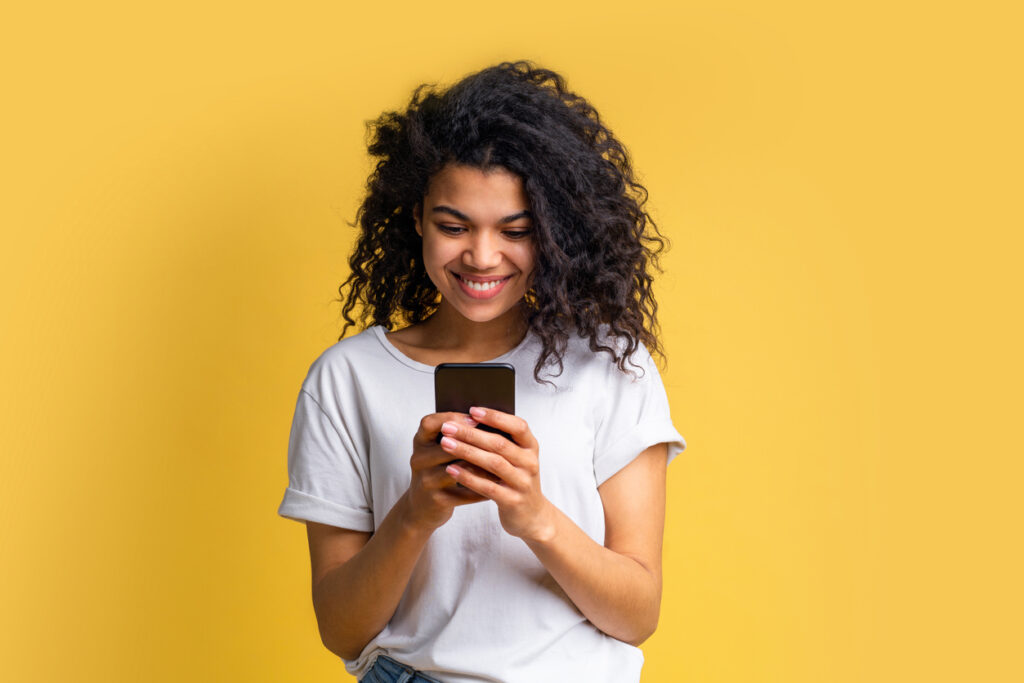 girl in white t-shirt using mobile phone with yellow background